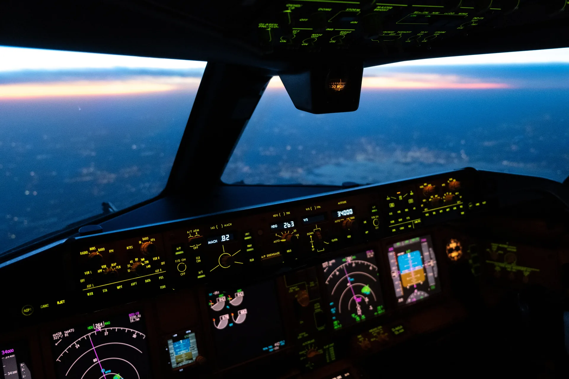 Cockpit de avião comercial em voo no entardecer